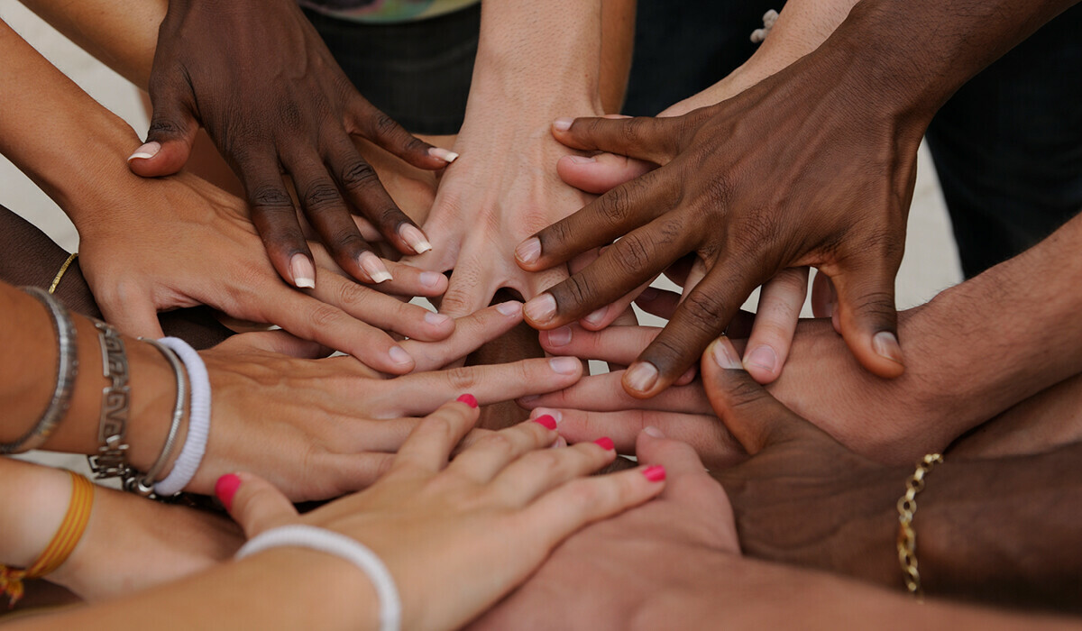 A group of diverse hands coming together in a circle, symbolizing support, unity and collaboration.